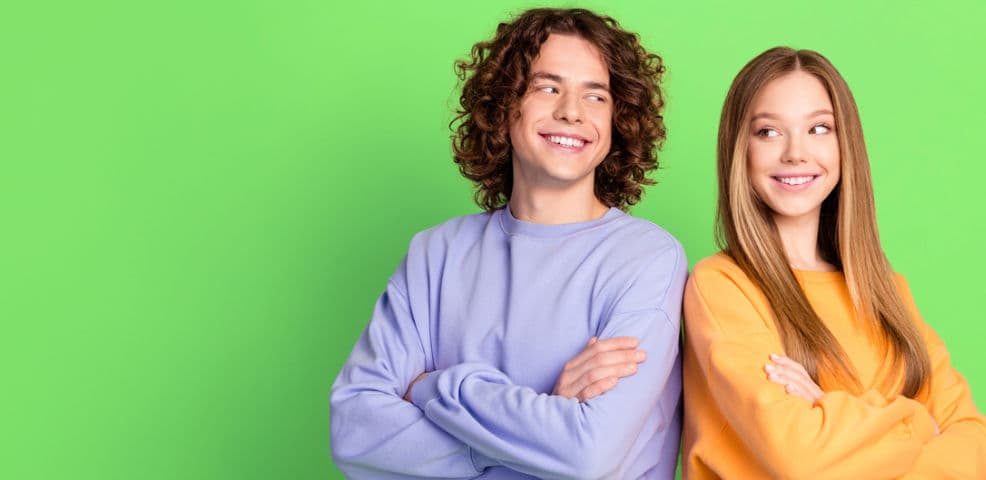 Smiling young man and woman standing confidently against a bright green background, promoting job alerts for teaching opportunities with JobsinED.