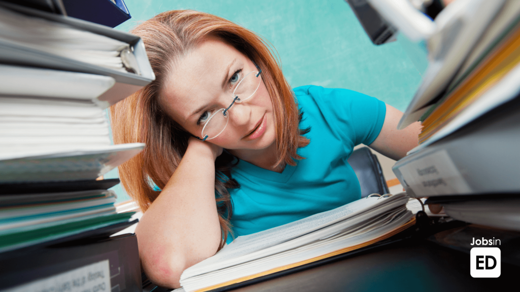 Stressed teacher overwhelmed with work and paperwork, highlighting challenges in teacher wellbeing.